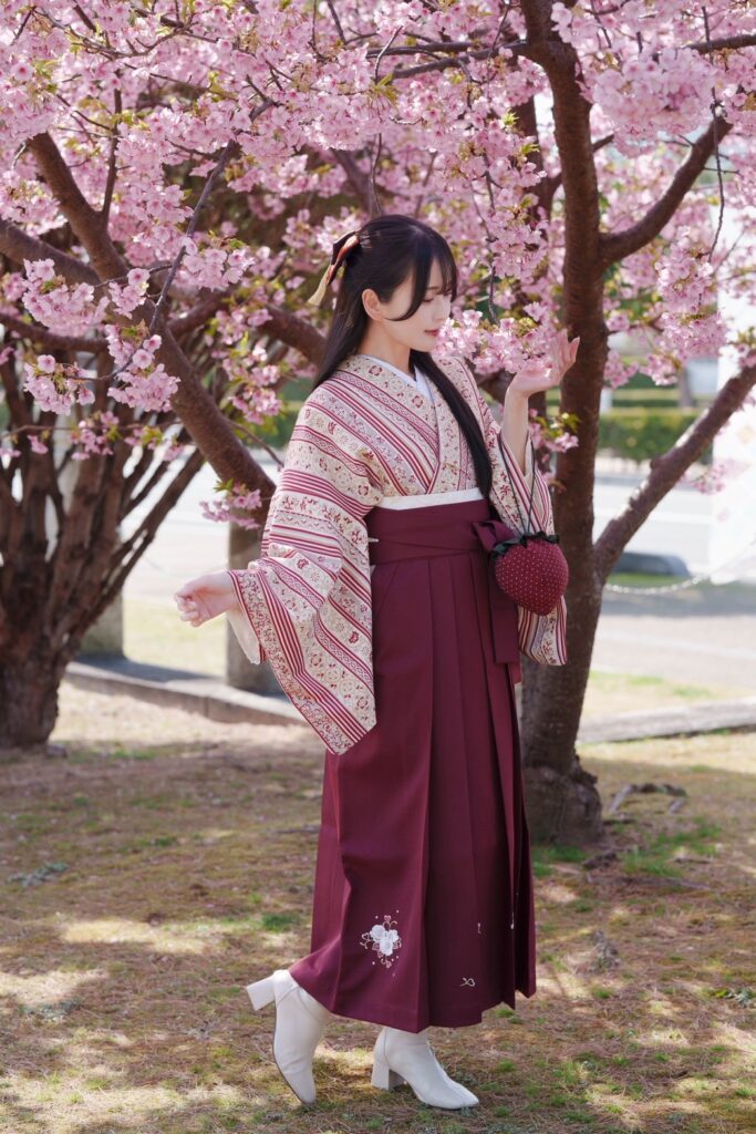 河津桜満開の前で袴姿でポーズをとる女の子